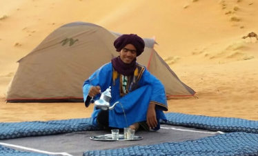 camelman pouring tea while desert camping