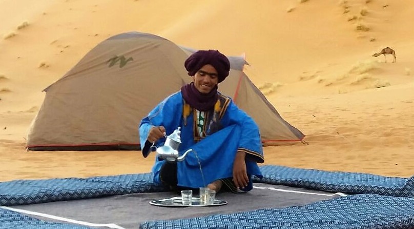 camelman pouring tea while desert camping