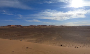 Erg Chebbi- big dunes in the distance, flat hamada in front, blue sky with some clouds