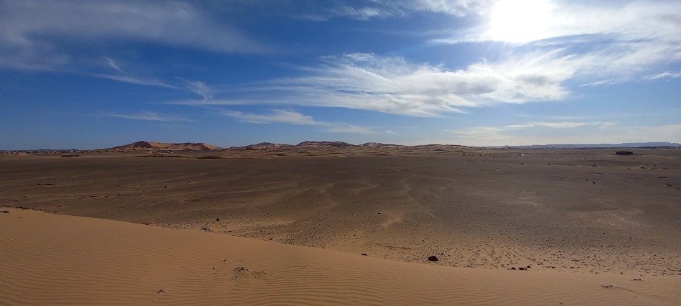 Erg Chebbi- big dunes in the distance, flat hamada in front, blue sky with some clouds