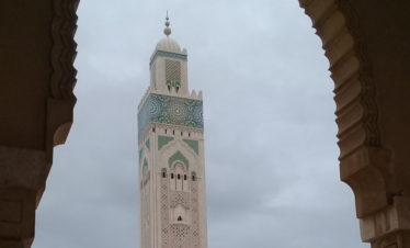minaret of Hassan II mosque seen through stone archway - Casablanca
