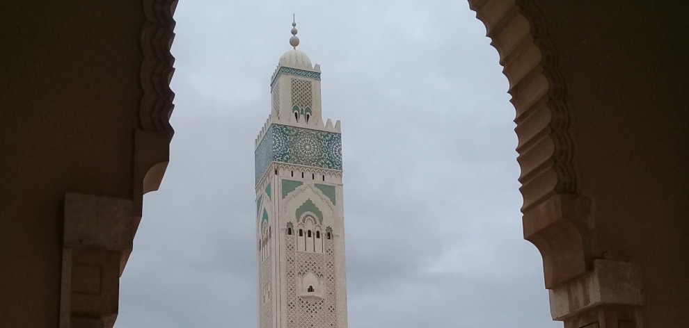 minaret of Hassan II mosque seen through stone archway - Casablanca