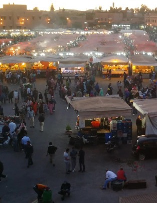 Marrakesh- overlooking the famous J'maa El Fnaa square at twilight, filled with people and covered stalls selling fresh cooked food